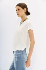 Remera blanca de lino con mangas cortas y calce al cuerpo. Presenta bordados de lentejuelas y mostacillas en los hombros.