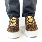 Championes urbanos con plataforma, de animal print color marrón y negro, con cordones dorados y cierre de cremallera lateral con tirador circular.