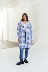 Camisa larga con estampado de rombos en tonos celeste, blanco y rosa. Tiene cuello camisero, cierre con botones y bolsillos frontales.