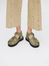 Sandalias romanas color verde oliva, con tiras entrecruzadas y hebilla lateral. Suela de goma negra con plataforma de 3cm. Fabricadas en cuero vacuno.