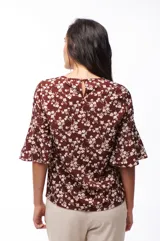 Blusa marrón con estampado floral blanco, de mangas cortas acampanadas y corte holgado.