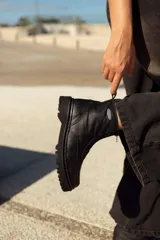 Bota de cuero negra con plataforma, caña baja y cierre frontal con cremallera.