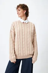 Sweater color beige con diseño de ochos en relieve, cuello redondo y corte oversize.