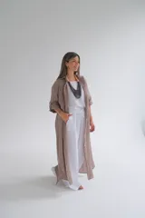 Camisola larga a rayas verticales color café, confeccionada en lino 100%. Tiene cuello camisero, mangas largas con botón ajustable y cierre frontal con botones.