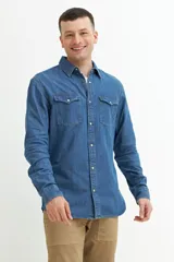 Camisa de manga larga de denim azul con dos bolsillos frontales con solapa abotonada.