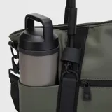 Bolso tote color verde oliva con detalles en negro. Tiene correa de hombro ajustable y extraíble, doble asa de mano, un compartimento principal con cierre, un bolsillo lateral externo, un compartimento interno para laptop de hasta 16 pulgadas y un bolsillo interno con cierre.