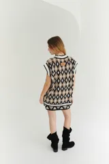 Chaleco tejido de lana con patrón de rombos en tonos lila, rojo y beige, con cuello en V y ribetes en color crema. Diseño oversize.