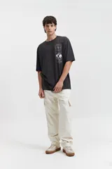 Remera negra de manga corta con corte oversize y estampado gráfico blanco en el frente que incluye un mapa del mundo y figuras geométricas.