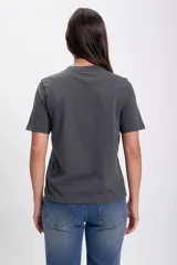 Remera gris oscuro de corte recto y mangas cortas, con estampa de un moño blanco en el centro.
