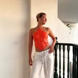 Top corto naranja con lentejuelas, escote halter y espalda descubierta. Se ata con tiras en la espalda y en el cuello.