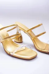 Sandalias plateadas con taco de forma geométrica y tiras transparentes.