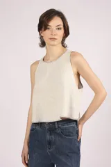 Blusa sin mangas color crema, con cuello redondo y bordes con pespuntes en contraste.