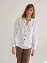 Camisa color crudo de corte recto y manga larga, con cuello mao y botones de madera. Presenta detalles de bordado calado en el frente.
