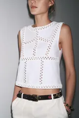 Top blanco de punto elástico con cuello redondo y sisa. Detalle de aplicación de crochet a contraste.