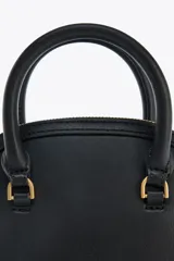 Bolso de mano color negro, con detalles metálicos dorados, bolsillo interior con cierre y correa extraíble para usar como bandolera.