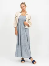 Vestido largo de lino azul claro con estampado de finas rayas verticales en color salmón. El corpiño es fruncido (smock) y el vestido tiene falda escalonada con volados.