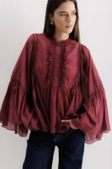 Camisa color marrón con cuello mao, mangas largas abullonadas y detalle de volados en el frente.
