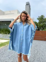 Camisola tipo poncho en jean celeste, con cuello camisero, abotonadura frontal y mangas cortas con volados.