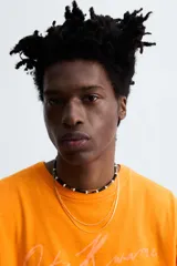 Camiseta naranja de algodón con cuello redondo y manga corta con vuelta. Estampado frontal con la firma del artista Otis Kwame Kye Quaicoe.