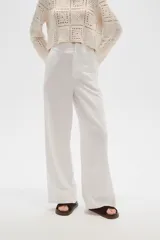 Pantalón blanco de lino, de corte recto y tiro alto, con bolsillos laterales.