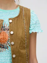 Chaleco corto de denim negro con apliques metálicos y flecos en el ruedo.