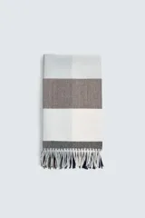 Bufanda rectangular con diseño a cuadros en tonos gris, blanco y marrón, con flecos en los extremos.