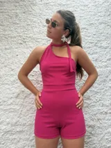 Mono corto fucsia con escote asimétrico halter y lazo al cuello.