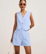 Short de sastre color marrón, de cintura alta, con bolsillos laterales decorados con tachuelas metalizadas y recortes delanteros.