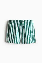 Short de baño blanco con rayas verticales verdes, cintura elástica con cordón ajustable, bolsillos laterales y bolsillo trasero con cierre autoadherente.