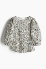 Blusa de tejido liviano con estampado de leopardo en blanco y negro. Modelo entallado con cuello redondo, cierre de botones y mangas globo tres cuartos con puños elásticos.