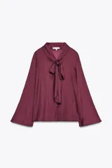Blusa color borgoña de cuello redondo con lazada en el mismo tejido y manga larga acampanada.