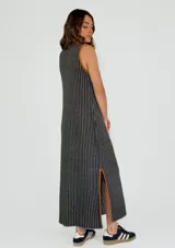 Vestido largo a rayas verticales color gris y blanco, con cuello en V y ribete amarillo. Presenta aberturas laterales con ribete amarillo.