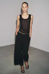 Pantalón cropped marrón de tiro medio y pierna ancha, confeccionado en hilatura con mezcla de lyocell. Presenta trabillas en la cintura, bolsillos laterales y pinzas en el delantero. Cierre frontal con cremallera y botón.