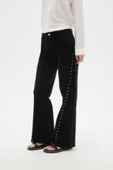 Pantalón jean negro de tiro alto, corte flare y detalle de tachas plateadas en los laterales.