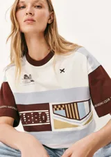 Camiseta de mangas cortas con cuello redondo y corte amplio. Presenta un diseño con bloques de color y estampados con motivos náuticos y geométricos.