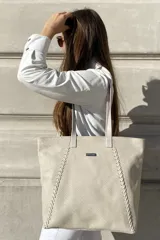 Bolso grande tipo tote de cuero color marrón con costuras decorativas en los laterales, forro interior con bolsillo para celular y bolsillo con cierre. Incluye bolsillo trasero con cierre y correas largas para colgar del hombro.