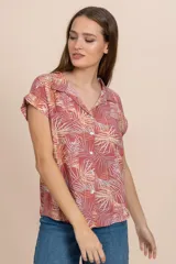 Camisa de manga corta color coral con estampado de hojas de palmera en tonos blanco y amarillo.
