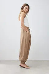 Pantalón tipo barrel color tostado, confeccionado en lino, con cintura elástica y cordón ajustable.