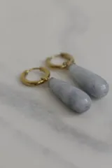 Par de aros colgantes con argolla dorada de acero quirúrgico hipoalergénico y dije en forma de gota de piedra natural blanca.