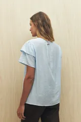 Blusa blanca de tela liviana con mangas cortas con volados y botón de nácar.