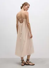 Vestido largo color rosa pálido con tirantes finos y escote en V. Tiene detalle de abalorios y cierre de lazo en la espalda.