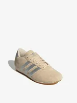 Zapatillas Adidas Taekwondo Lace W color beige con las tres tiras plateadas y refuerzo plateado en el talón.