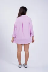 Camisa negra de corte amplio, con cuello clásico, cierre frontal con botones, manga larga con puños arremangados y bolsillo de parche en el pecho.