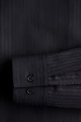 Camisa de manga larga color negro con finas rayas verticales, cuello inglés, tapeta clásica, bolsillo superior abierto, canesú con pliegue de caja en la espalda y bajo redondeado.