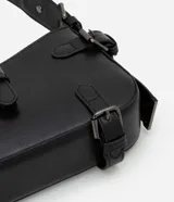 Bolso baguette pequeño de cuero sintético negro con solapas y hebillas decorativas. Cierre con cremallera y forro de poliéster.