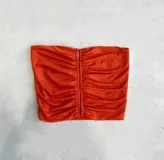 Top strapless color ladrillo con frunce en el frente y detalle de aberturas verticales.