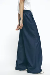 Pantalón de tiro alto azul denim, con cintura elástica ajustable con cordón, bolsillos laterales y traseros, y pernera ancha.
