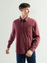 Camisa de manga larga color verde oliva, confeccionada en algodón. Tiene corte clásico, bolsillo en el lado izquierdo del pecho y cierre con botones.