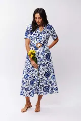 Vestido midi de algodón con estampado floral en tonos azul y blanco, corte camisero, cuello clásico, mangas cortas y cinturón con hebilla redonda de madera.