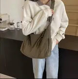 Bolso hobo color bordó de tela suave, liviana y espaciosa, con bolsillos frontales con cierre y correa ajustable.